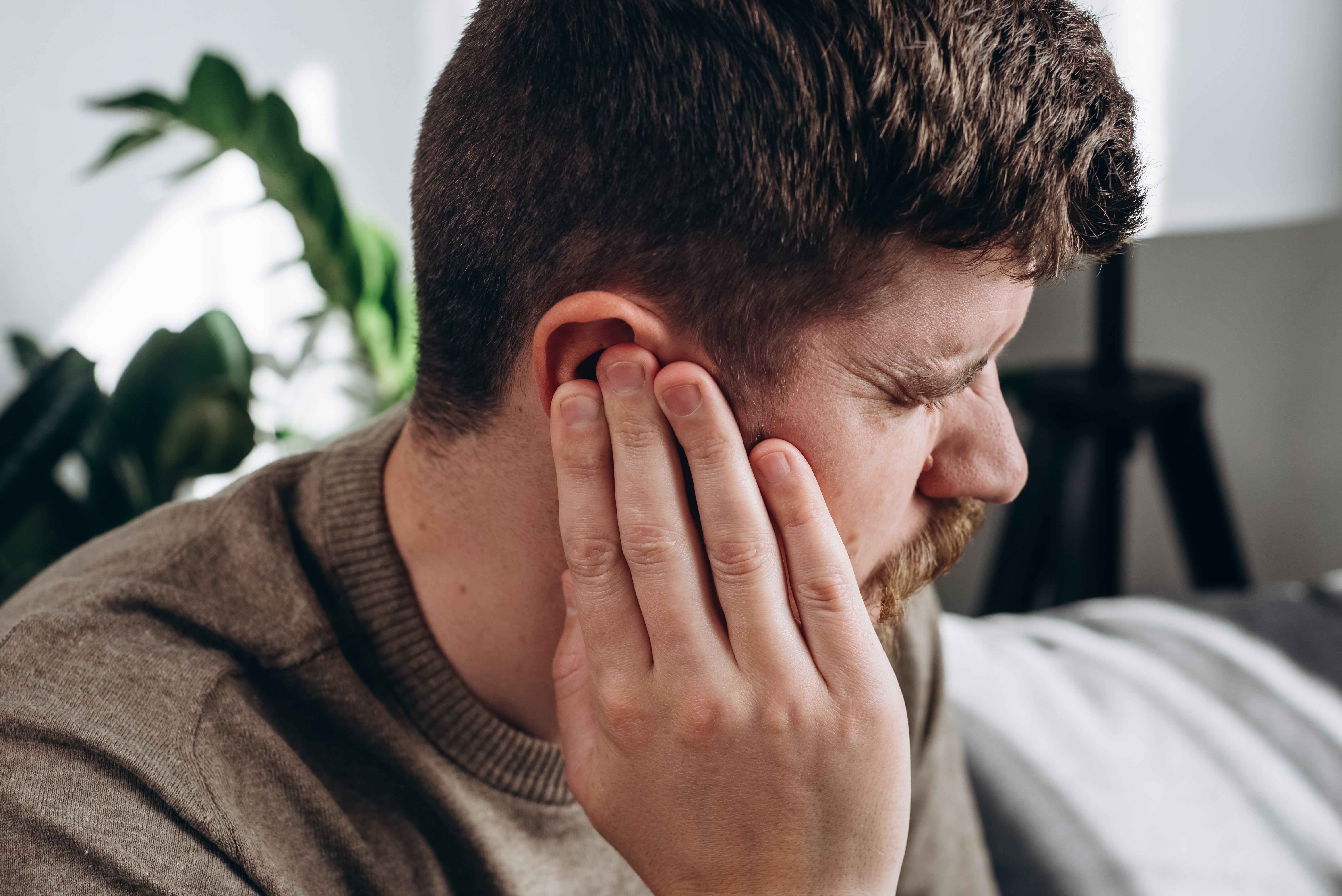 A man closes his eyes and holds his hand over his ear